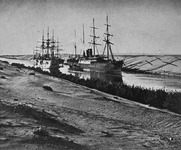 A Black and white photograph of two steamships sailing through a canal in the desert.