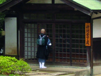 Fig. 8. A photograph of a person wearing monastic traveling gear, waiting at a traditional Japanese door.