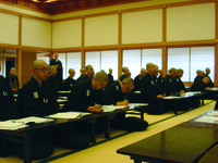 Fig. 9. A photograph of a classroom of temple students, many bald-headed and wearing glasses, as they listen attentively and take notes.