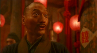 A man with a surprised look on his face. In the background is a poster with the character for double happiness.