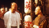 Two individuals converse in front of lanterns with white calligraphy printed on them.