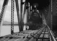 This photo depicts a train traveling across a bridge over water.