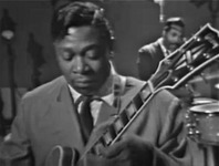 Figure 8. B. B. King plays a guitar solo with his head tilted down toward the instrument and his eyes closed in an expression of deep concentration on the music.
