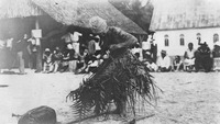 Black-and-white photograph of a Cook Islands performer dressed in a canoe costume made of coconut leaves.