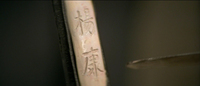 The name of the protagonist is carved into the handle of a sword with another sword.