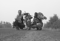 The author and one of his informants crouch next to a bicycle on a dirt road.