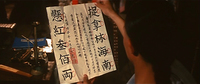 A person reads a calligraphic note with large and small characters.