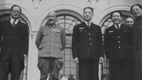 This photo shows six figures standing in front of a Western-­style building. Mamoru Shigemitsu, bespectacled and wearing a tuxedo, has a faint smile on his lips while looking into the camera. Tōjō Hideki alone is dressed in a military uniform. Bald, mustached, wearing round glasses with black rims, in a uniform decorated with rows of medals, his pants tucked into boots, and his arms folded behind him, Tōjō is smiling, seemingly relaxed. Wang Jingwei, in a dark and buttoned-­up suit, is pressing his lips into a faint smile. His arms are hanging naturally. Chen Gongbo, in the same dark suit as Wang’s, and Zhou Fohai, in a dark magua jacket over a long robe, are both laughing in good spirits.
