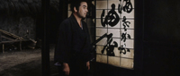 A man stands in front of the shoji with black calligraphy printed on it.