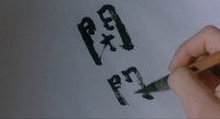 Black calligraphy being written on a white background.