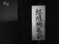 Black calligraphy on a white banner, in the dark.