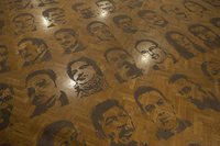 Photo of a wooden surface with faces printed onto it in a grid.