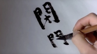 Black calligraphy being written on a white background.