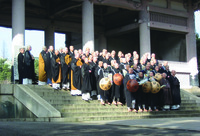 Fig. 11. A photograph of large group of people wearing monastic clothing assemble on the steps leading to a temple gate for a photo.
