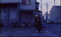 Closed garage doors, streetside bannes, an a window have red, white and black calligrpahy printed on them.