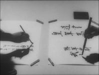 Two individuals brush calligraphy onto two seperate pieces of mounted paper, in black and white cinematography.