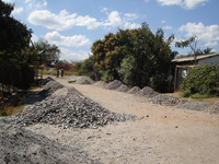 Photograph of a street lined on its sides with tidy heaps of flux stone from nearby mining dump site.