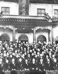 This blurred black-­and-­white image shows the upper echelon of the RNG government in Nanjing taking a group photo in front of a building of hybrid (Chinese and Western) style, with the calligraphic characters “[Guo]min zhengfu” (national government) visible on a vertical plaque hanging on the front of the building. Wang Jingwei, in black suit and tie, is sitting in the middle of the first row. Of the circa eighty people surrounding him, most are civilians in dark clothes and white shirts. A few military leaders in uniform can also be spotted, but mostly standing in the back rows.