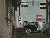 Ozu's films often have shots that show an alley-full of signs. The prominent sign on the left is in hiragana, and is so well-known that it the prop was put on display during an Ozu exhibition and that National Film Archive of Japan.