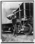 Fig. 24. A young man in casual clothes, sports cap, and a sack slung over his shoulder has one foot up on a boxcar as he pulls himself on to the train.