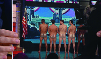 Television host Stephen Colbert holding a photo of men baring their naked bottoms, branded with the Hillary Clinton’s campaign phrase “I’m with Her.”