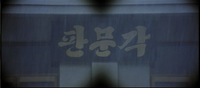 A subjective view shows rain obscuring a banner with white calligraphy.