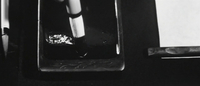 A brush is put in ink in close-up, in black and white cinematography.