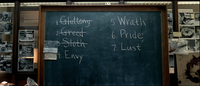 A chalkboard in the police station lists the seven deadly sins.