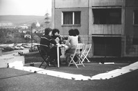 In this picture of a 1978 performance, Slovak artist Ján Budaj and three colleagues have a normal lunch, staged in the parking lot of a typical communist-era apartment building. A microphone placed on the table broadcasts their intimate conversation to onlookers.