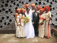 Family members in aso ebi pose around a bride in front of a textile background.