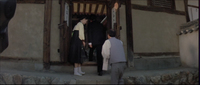 A man walks through a doorway with banners with black calligraphy posted on the inside of the doors.