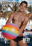 A man wearing a bathing suit holds a beach ball and while standing in front of a photo of the beach.