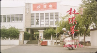 Opening credit for director Johnny To is written horizontally in red, typefaced English on the bottom, right edge. The Chinese name is brushed, while the role is rendered in typeface. These are superimposed over a screenscape of a motocycle arriving at a building.