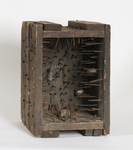 A wooden box lined with nails, containing three loose stones that produced sound when the box was moved.