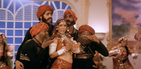 Medium shot of Champa (Neena Gupta, with Ila Arun as the playback voice) as a banjarin dancer in “Choli Ke Peeche” in Khalnayak. Sporting a red ghaghra-­choli and heavy silver and white jewelry, she is surrounded by four male dancers and stares confidently at the camera.