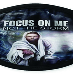 This photograph shows a black mask with the image of Jesus Christ standing his hand, with the title Focus on Me, Not the storm. The background is of a large ocean wave and a boat facing the storm.