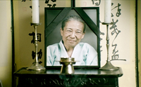 A framed picture of the deceased is in front of banners with black calligraphy.
