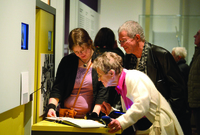 Three people looking at and handling a book.