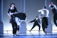 Dancers dressed in black-and-white nineteenth-century silhouettes with red accents. Liu, downstage, is leaping into the air, supported by Chamberlin, while Brown, upstage, lunges to the left, right arm outstretched behind him. Leonard is pictured midspin, his back to the camera. Montes just enters the frame as he leaps into the air, arms lifted overhead and crossed at the wrists.