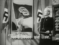 A classroom of a German elementary school, children are singing the hymn for Hitler and the lines are shown in English at the bottom, white typed letter