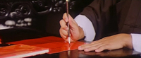 Man in the process of writing on a red piece of paper