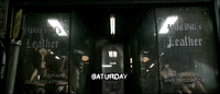 A scratched "Saturday" is framed by blackletter calligraphy on the shopwindow.