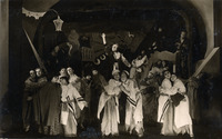 Black-and-white photograph of a large group of actors on stage in costume.