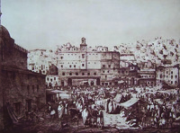 Black-­and-­white drawing of a city scene with several people outside of large buildings in the foreground and smaller buildings on a hillside in the background.