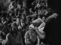 Black and white image of someone reading a letter to a large group of soldiers. The letter was written in black vertical calligraphy.