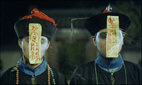 A line of individuals have streamers attached to their hats covering their faces with red calligraphy.