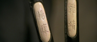 A closeup of two names of protagonists carved into metal sword handles.