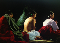 A woman with a sutra painted on her skin prays in a group.