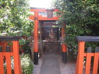 Photograph of red torii gate and a small altar.