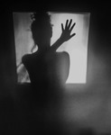 Black-and-white photograph of the shadow of a female silhouette at the center.